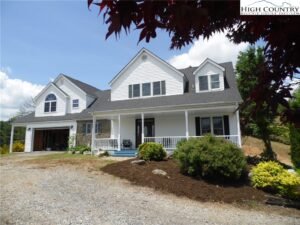 a gorgeous, two-story home in Blowing Rock NC, painted white with a large porch on the front