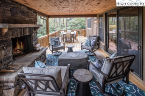 a lovely outdoor porch and seating area at a Blowing Rock house for sale, with a stone fireplace on the left hand side